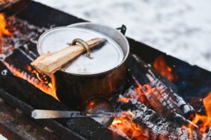 silver pot on campfire with ladle