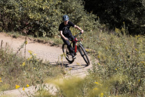 man riding red mountain bike on dirt path